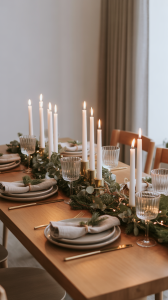 Minimalist Christmas dinner table decorated with candles, greenery, and simple table settings.